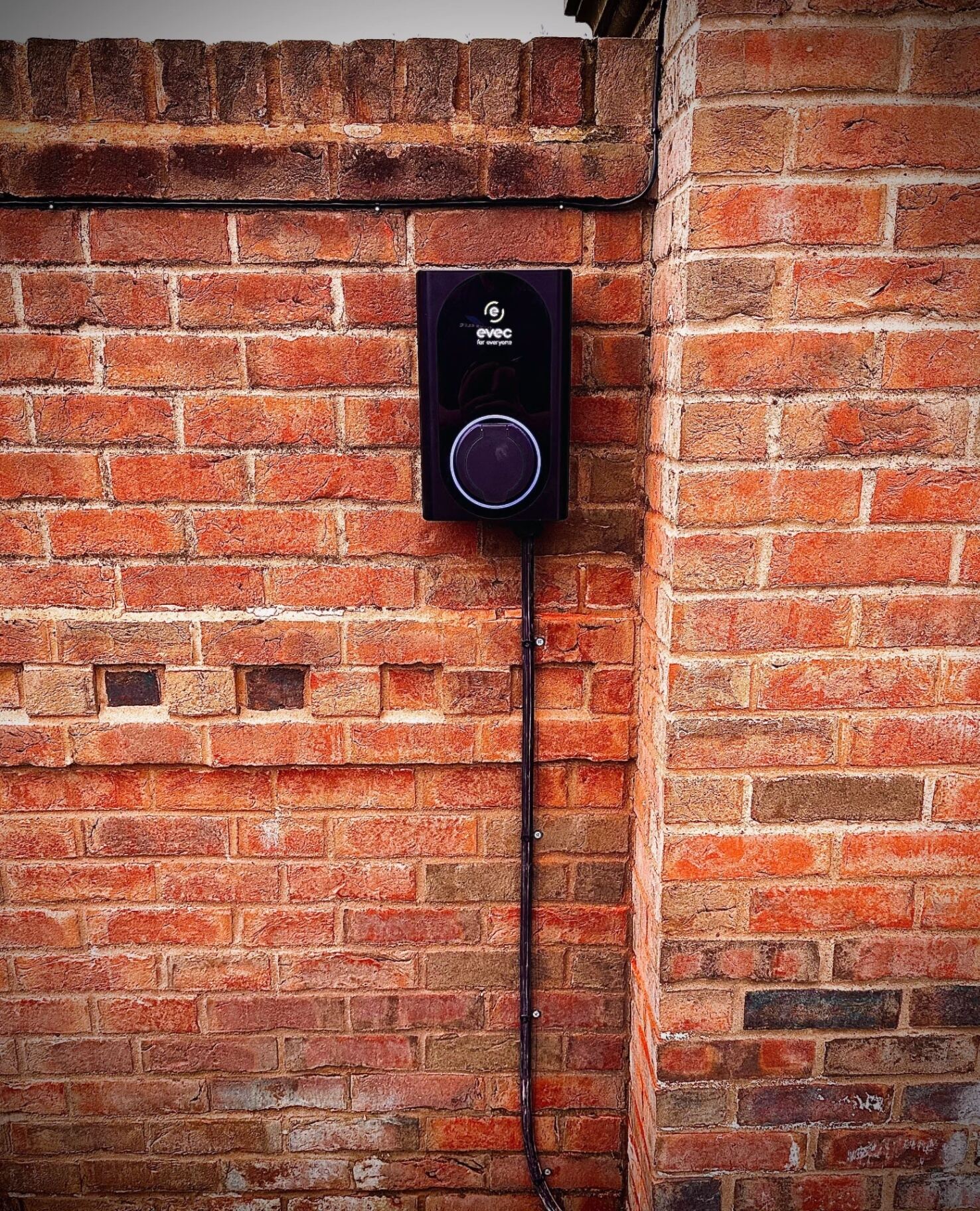 Home EV charge point installed on a brick wall