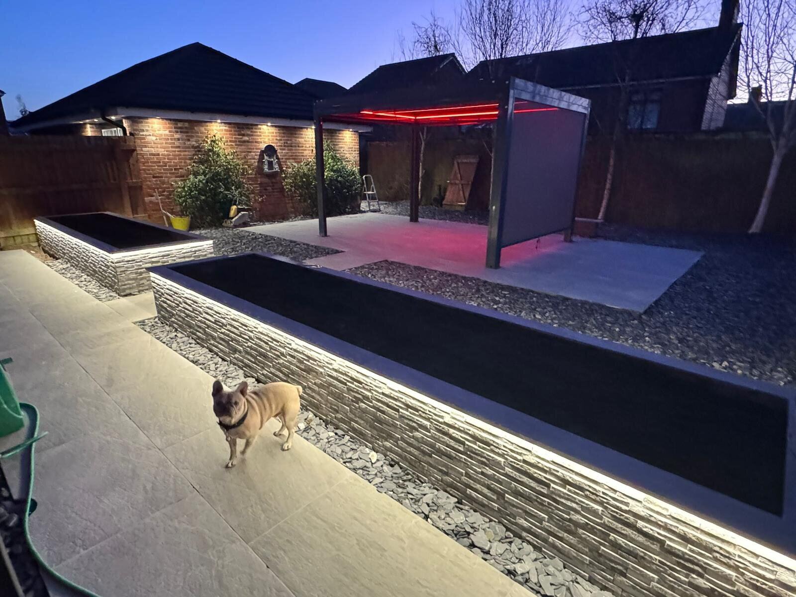 Exterior garden lighting scheme with LED pergola and raised bed strip lights at dusk