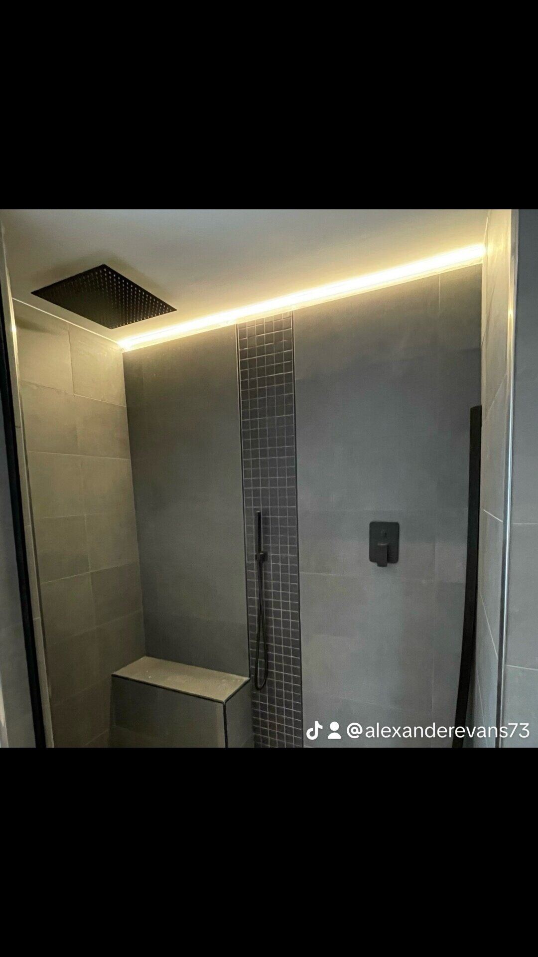 Walk-in shower with concealed LED strip lighting and dark contemporary fittings installed by Northern Tec